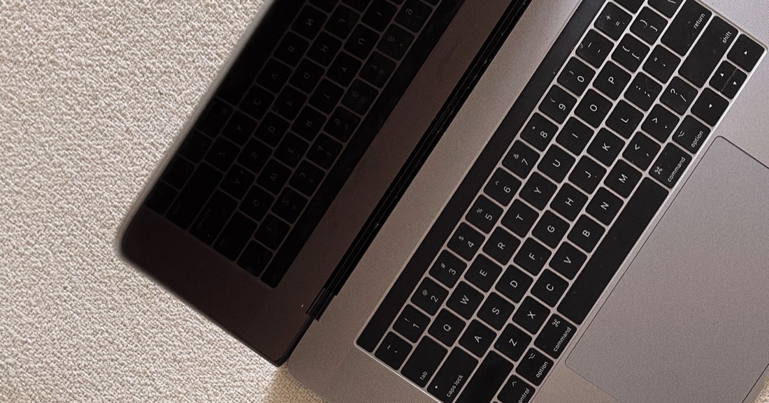 An open laptop resting on a cream textured rug.