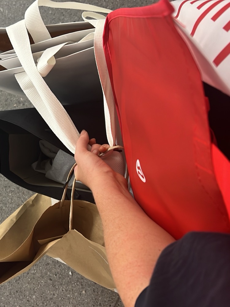 A handful of retail shopping bags carried through a shopping centre.